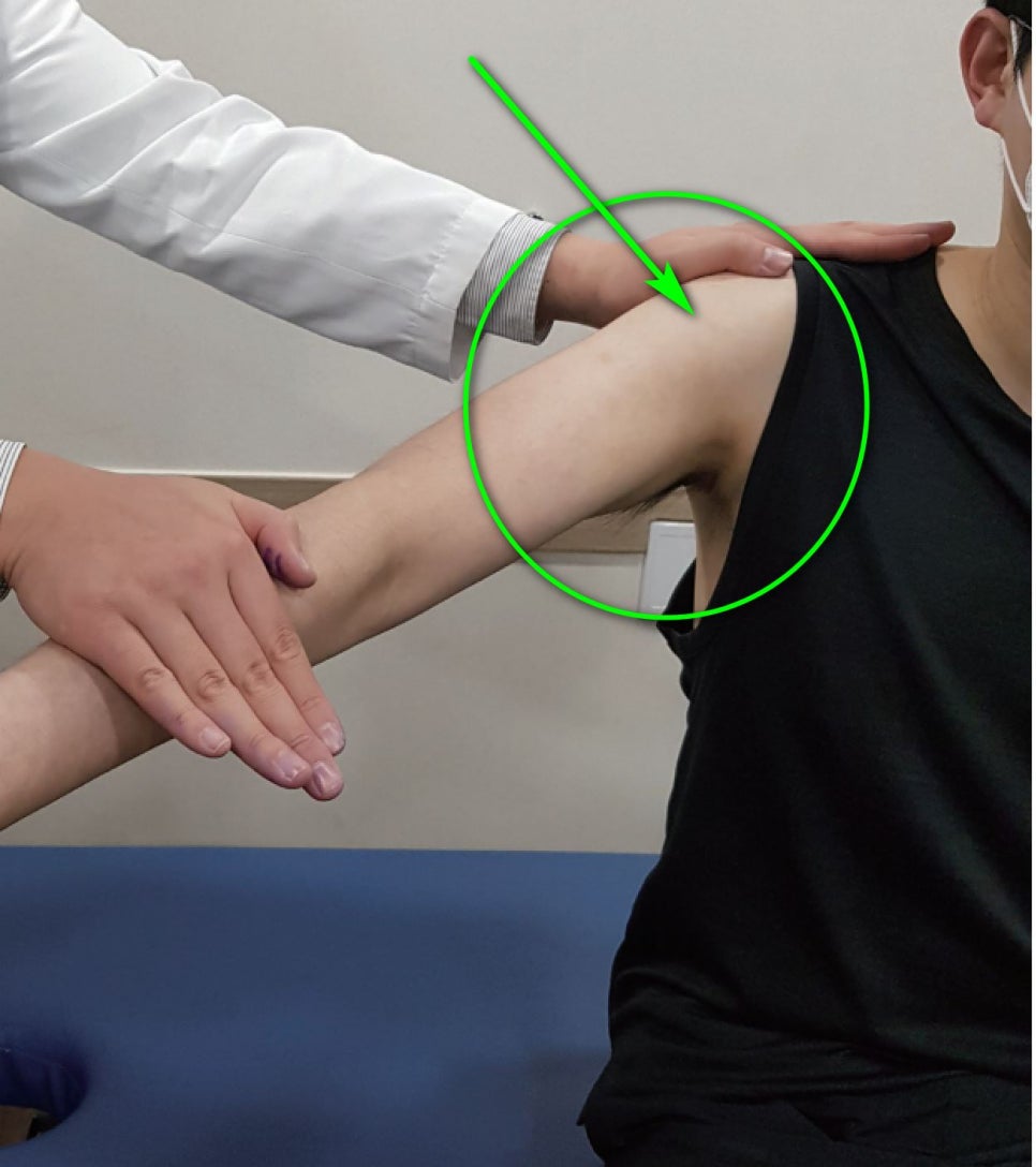한의사가 환자의 어깨를 진찰하며 초록색 원과 화살표가 어깨 부위를 가리키고 있는 모습 — 초음파 약침·도침 임상 논문 | 서울 바로한의원