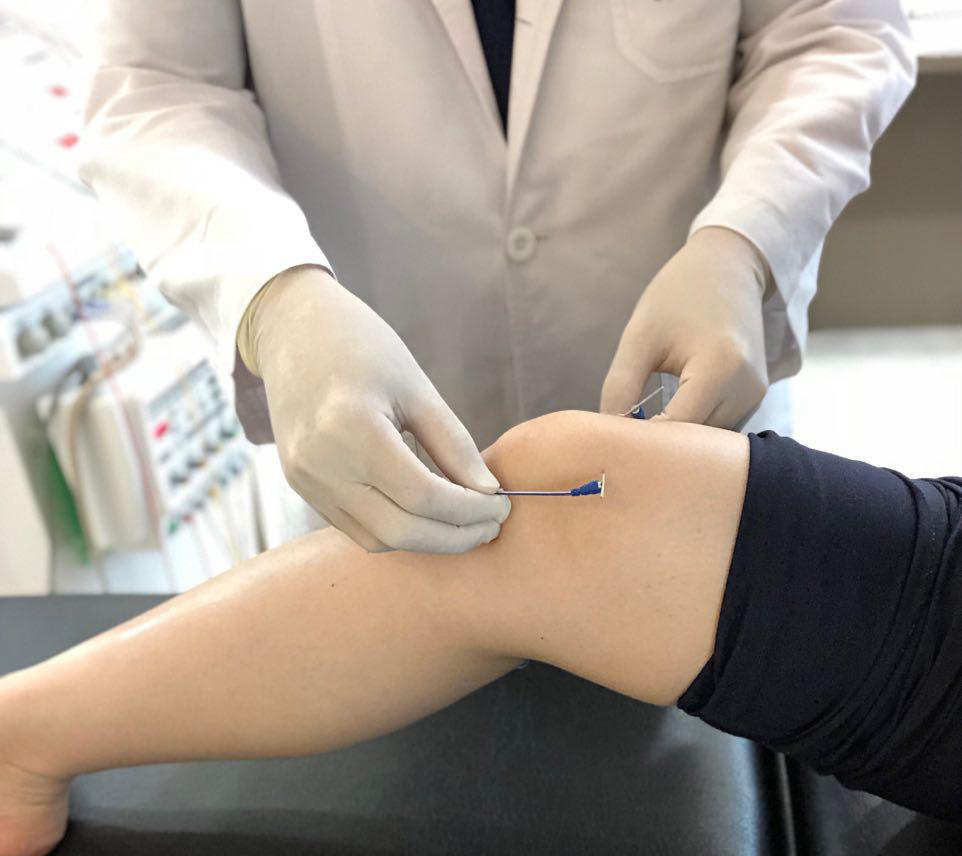 한의사가 장갑을 끼고 환자의 무릎에 매선 시술을 하는 모습 — 초음파 유도하 약침 시술 | 서울 바로한의원