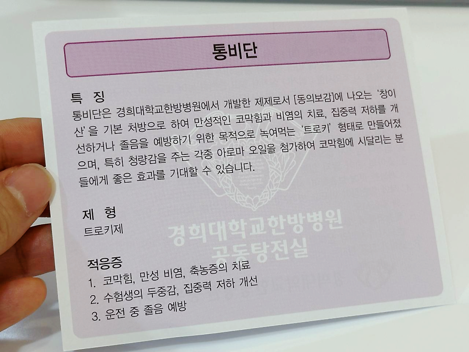 손이 통비단 제품의 특징, 제형, 적응증이 적힌 안내문을 들고 있는 모습 — 서울 바로한의원 초음파 약침·도침