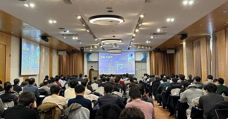강의실에서 많은 사람들이 앉아 강연을 듣고 있다. 강단 뒤 스크린에는 '경혈 초음파'라는 제목과 초음파 영상이 보인다 — 대한한의영상학회 초음파 약침·도침 강의 | 서울 바로한의원