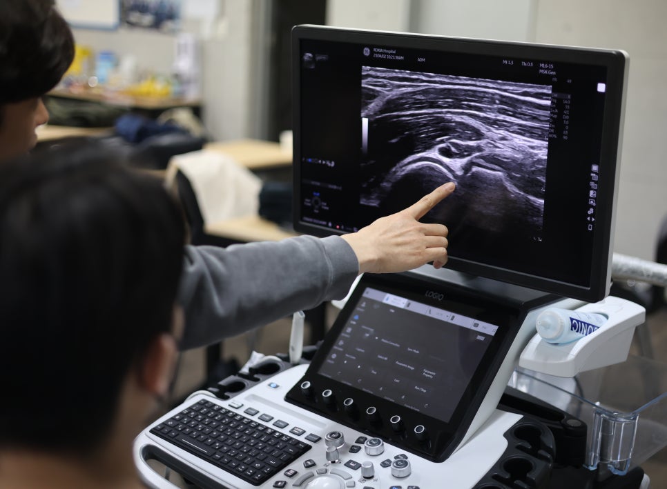 한 사람이 초음파 기기 화면에 보이는 관절 초음파 이미지를 손가락으로 가리키고 있다 — 초음파 정밀 진단 | 서울 바로한의원 초음파 약침·도침·침도