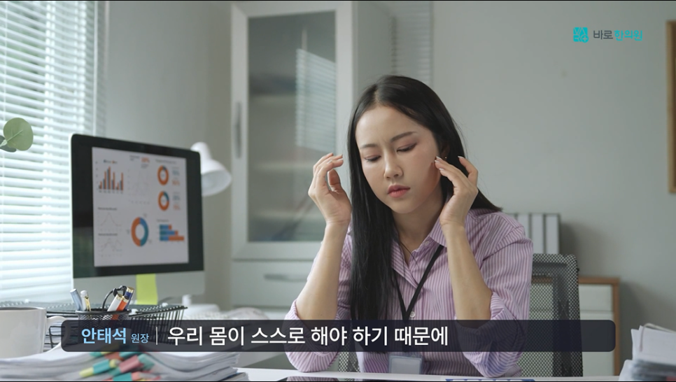 사무실 책상에 앉아 머리를 감싸 쥐고 있는 여성 — 서울 바로한의원 초음파 약침·도침