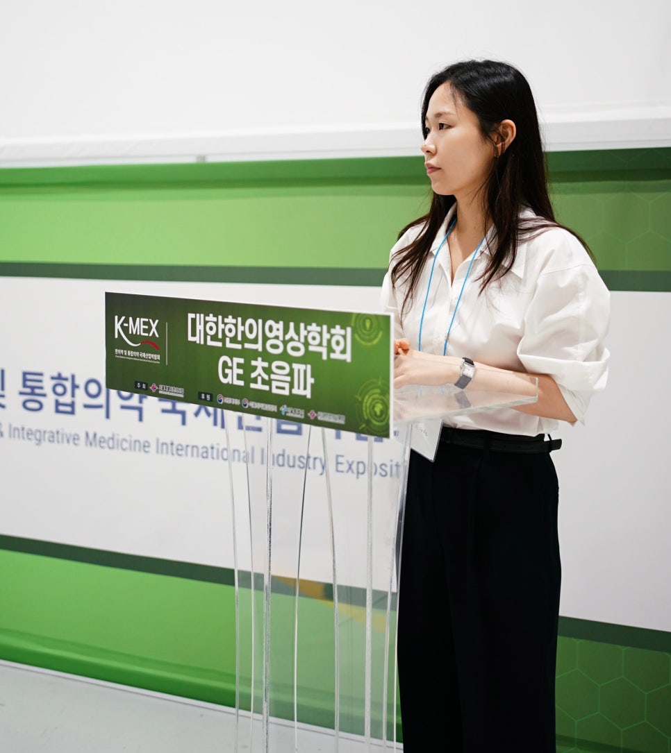 한의영상의학회 GE 초음파라고 적힌 연단 옆에 서 있는 여성 — 대한한의영상학회 초음파 약침·도침 강의 | 서울 바로한의원 문지현 원장