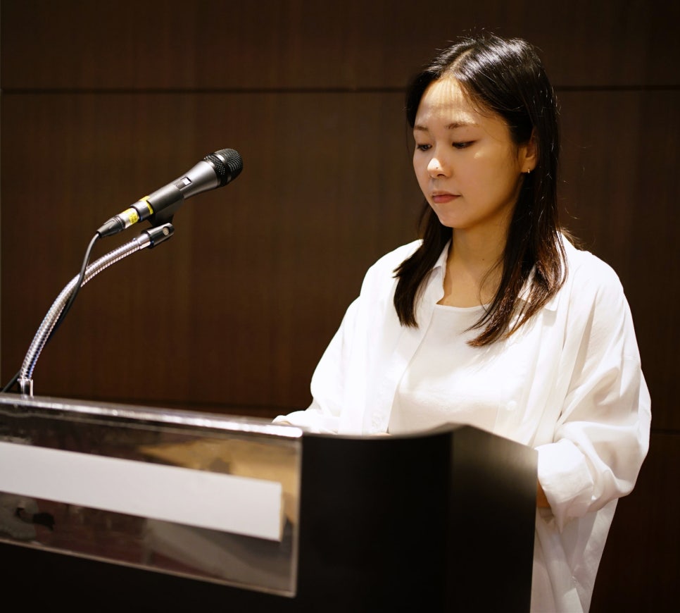 마이크가 있는 연단에 서서 아래를 보고 있는 여성 — 대한한의영상학회 초음파 약침·도침 강의 | 서울 바로한의원 문지현 원장