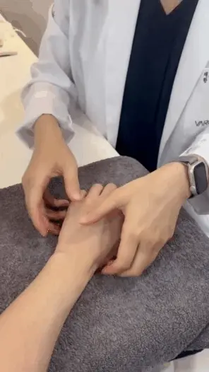 흰색 가운을 입은 사람이 다른 사람의 손목과 손을 만져 진찰하는 모습 — 서울 바로한의원 초음파 약침·도침